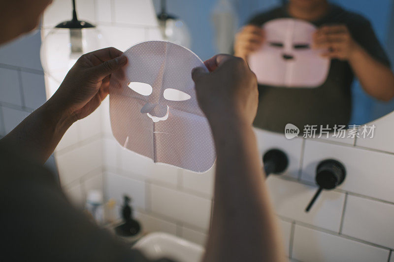 asian chinese man in front of bathroom mirror applying facial mask